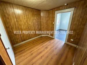 Empty room featuring wood finished floors, wooden walls, a smoke detector, and a textured ceiling