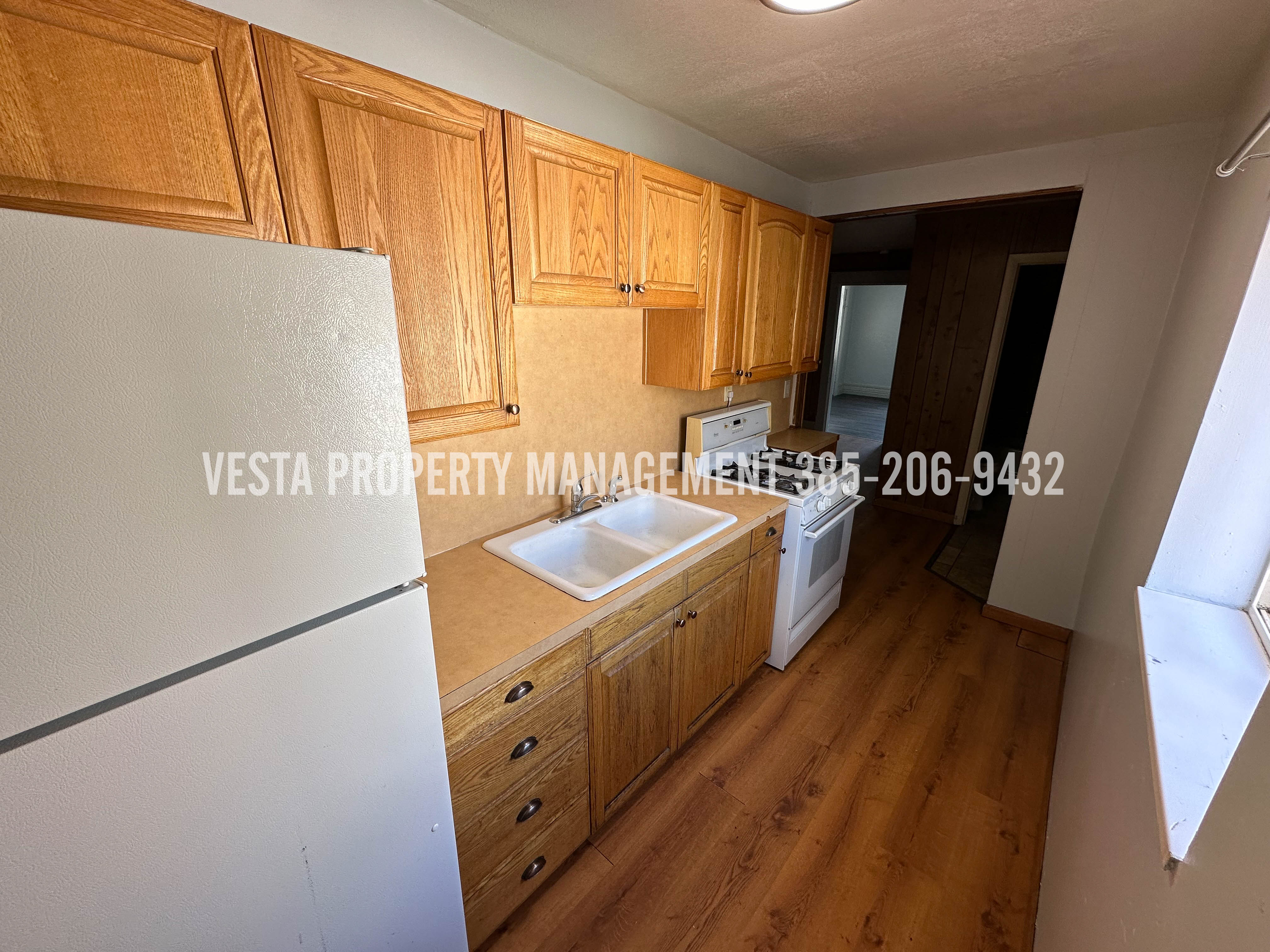 Kitchen featuring white appliances, light countertops, and wood finished floors