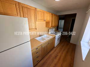 Kitchen featuring white appliances, light countertops, and wood finished floors