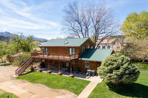 Rear view of house featuring a deck with mountain view, a lawn, and a metal roof