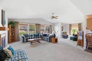Living area with light carpet, a ceiling fan, and a fireplace