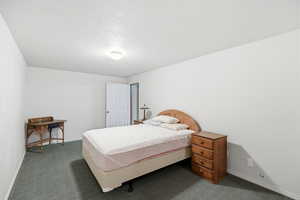 Bedroom featuring dark colored carpet and a textured ceiling