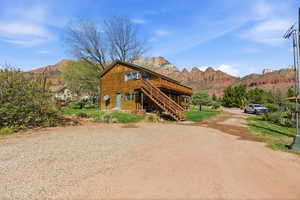 View of front of home featuring a front yard, a deck with mountain view, driveway, and a patio area