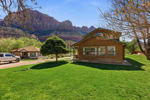 View of property exterior with a mountain view, a lawn, and dirt driveway