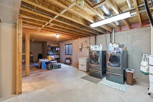 Unfinished below grade area featuring washing machine and clothes dryer
