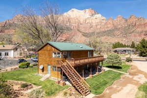 Rear view of house featuring a lawn, a deck with mountain view, and a metal roof