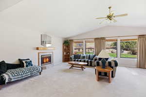 Living area featuring light colored carpet, ceiling fan, and a tile fireplace