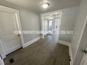 Hall featuring a textured ceiling and dark wood finished floors