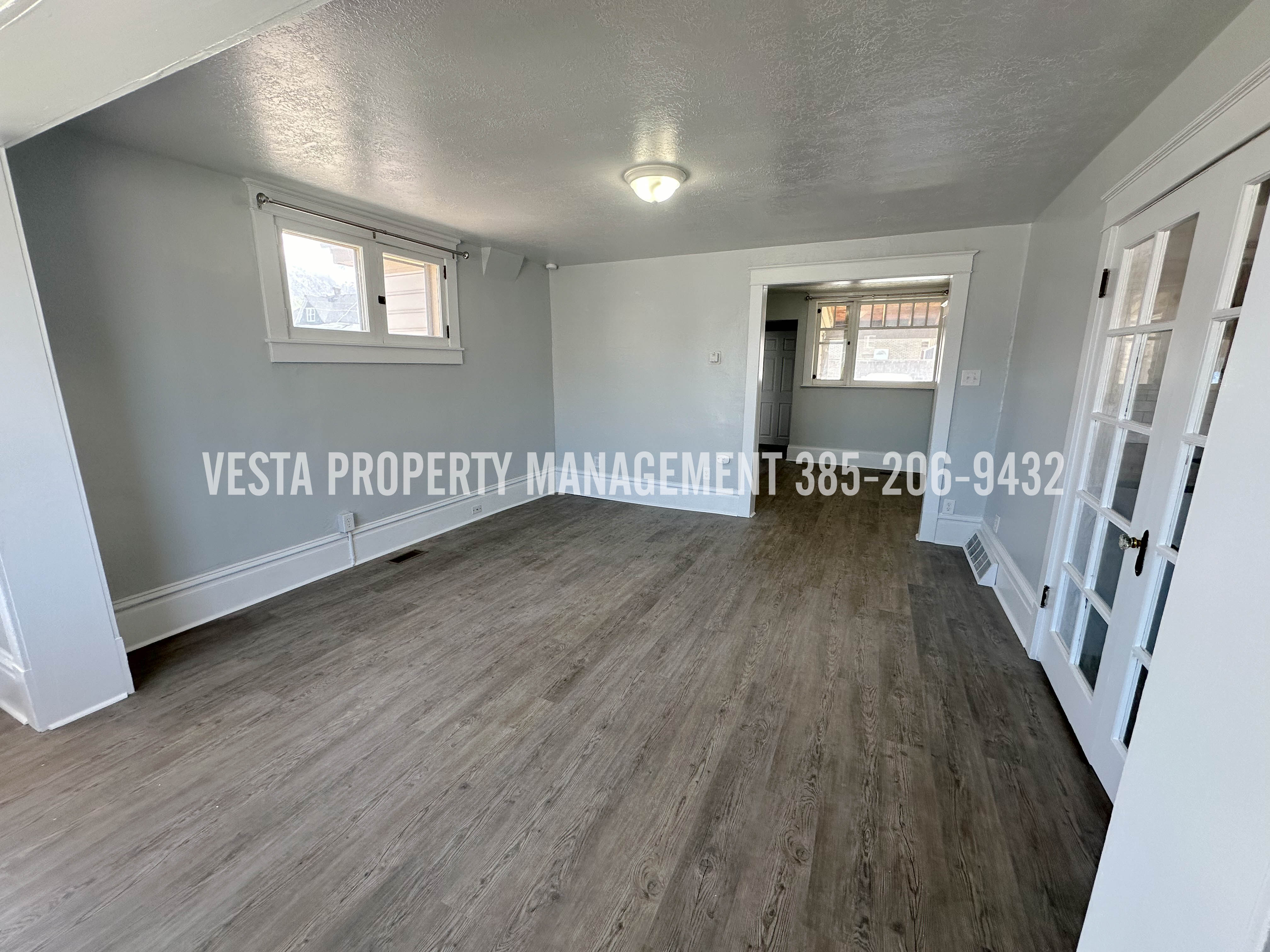 Spare room with a textured ceiling, dark wood-style flooring, and healthy amount of natural light
