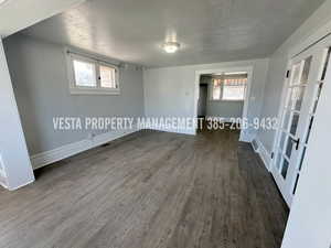 Spare room with a textured ceiling, dark wood-style flooring, and healthy amount of natural light