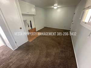 Unfurnished room with dark carpet and a textured ceiling