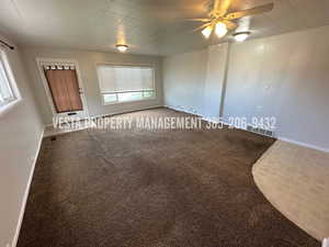 Unfurnished room featuring carpet flooring, a ceiling fan, and a decorative wall
