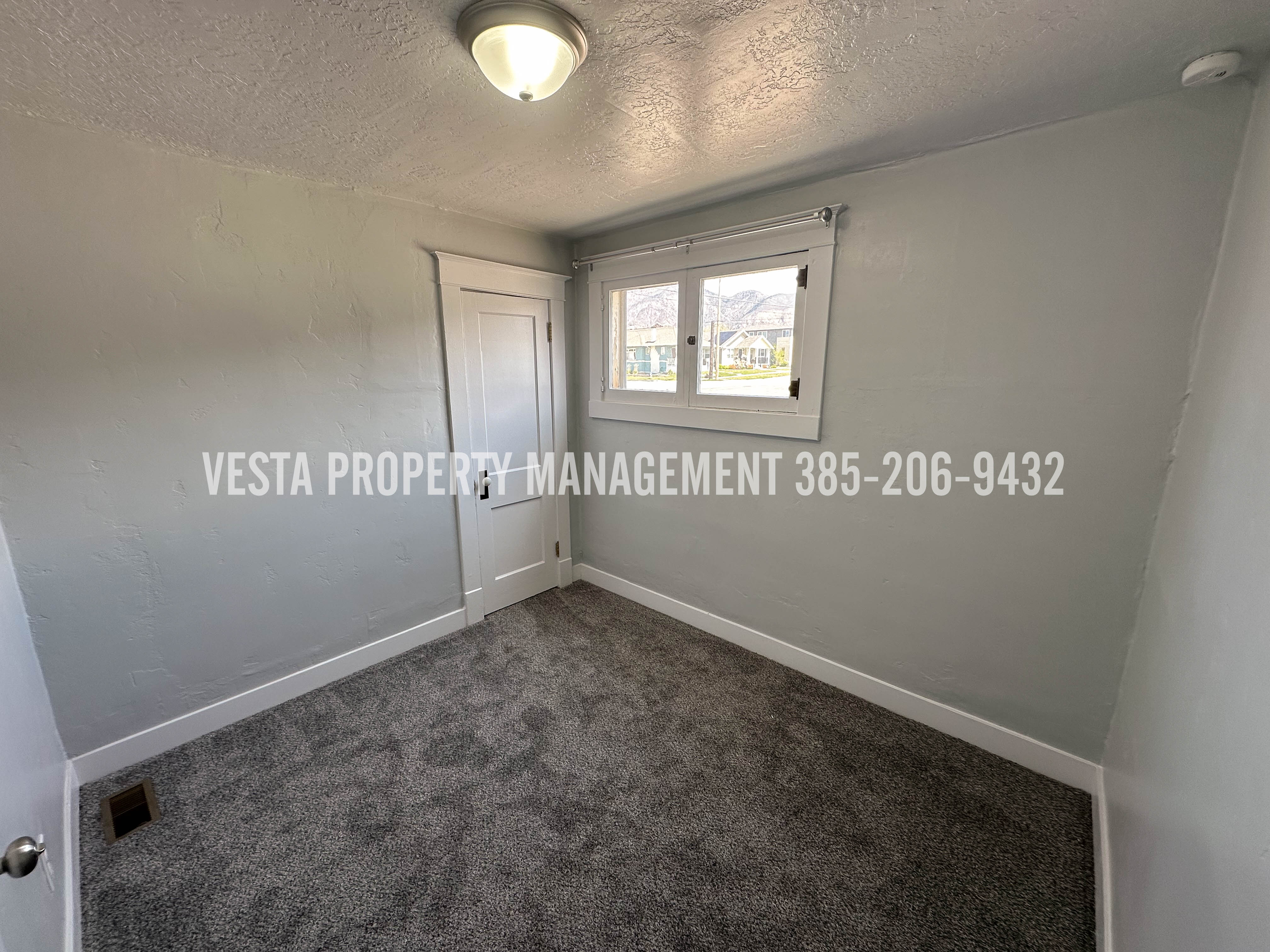 Spare room with dark carpet, a textured ceiling, and a smoke detector