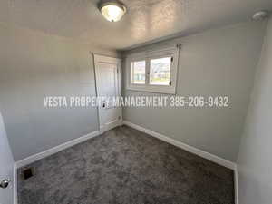 Spare room with dark carpet, a textured ceiling, and a smoke detector