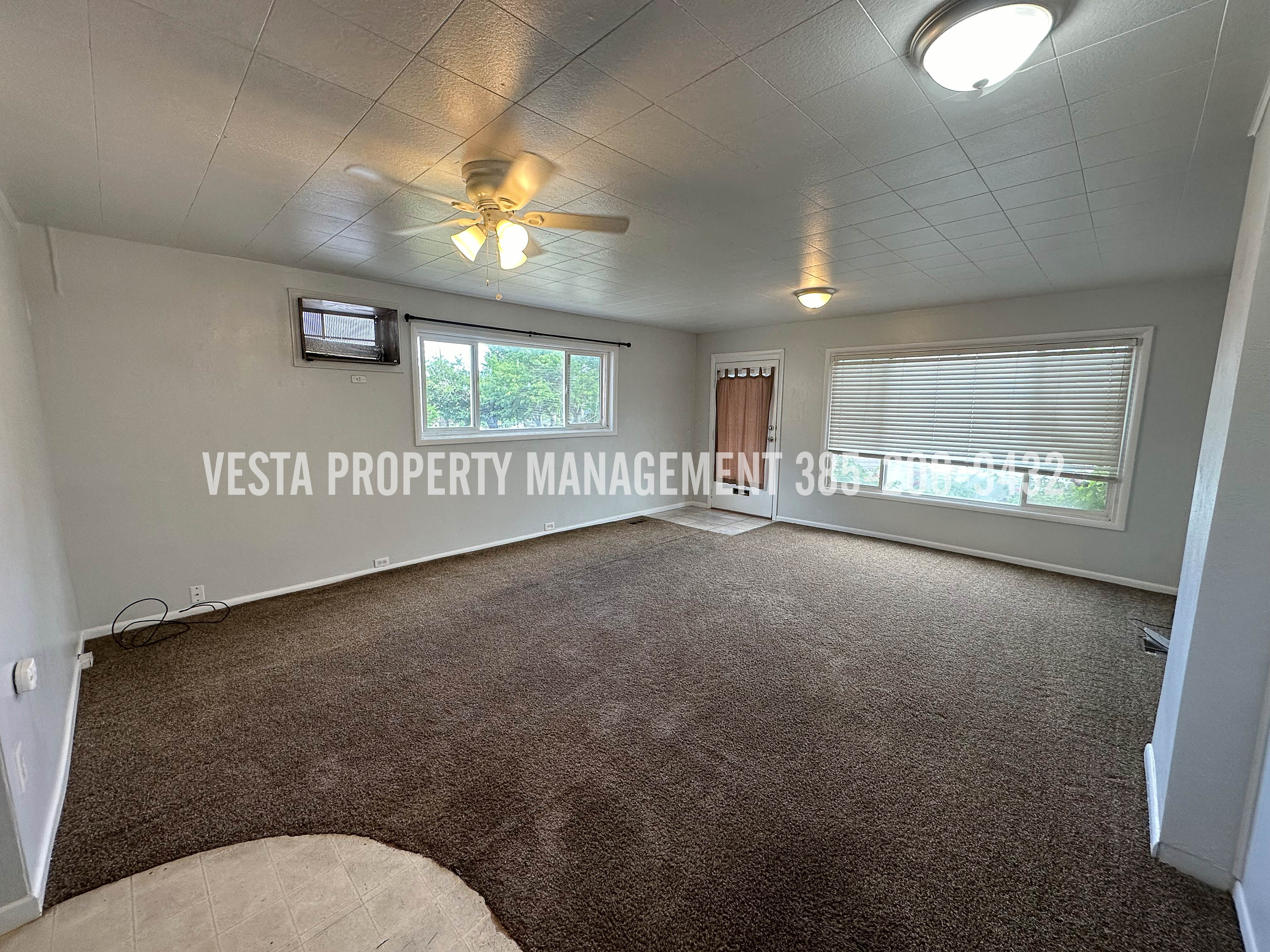 Carpeted empty room with a ceiling fan and baseboards