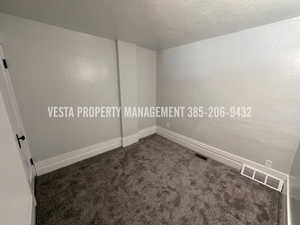 Spare room with dark colored carpet and a textured ceiling