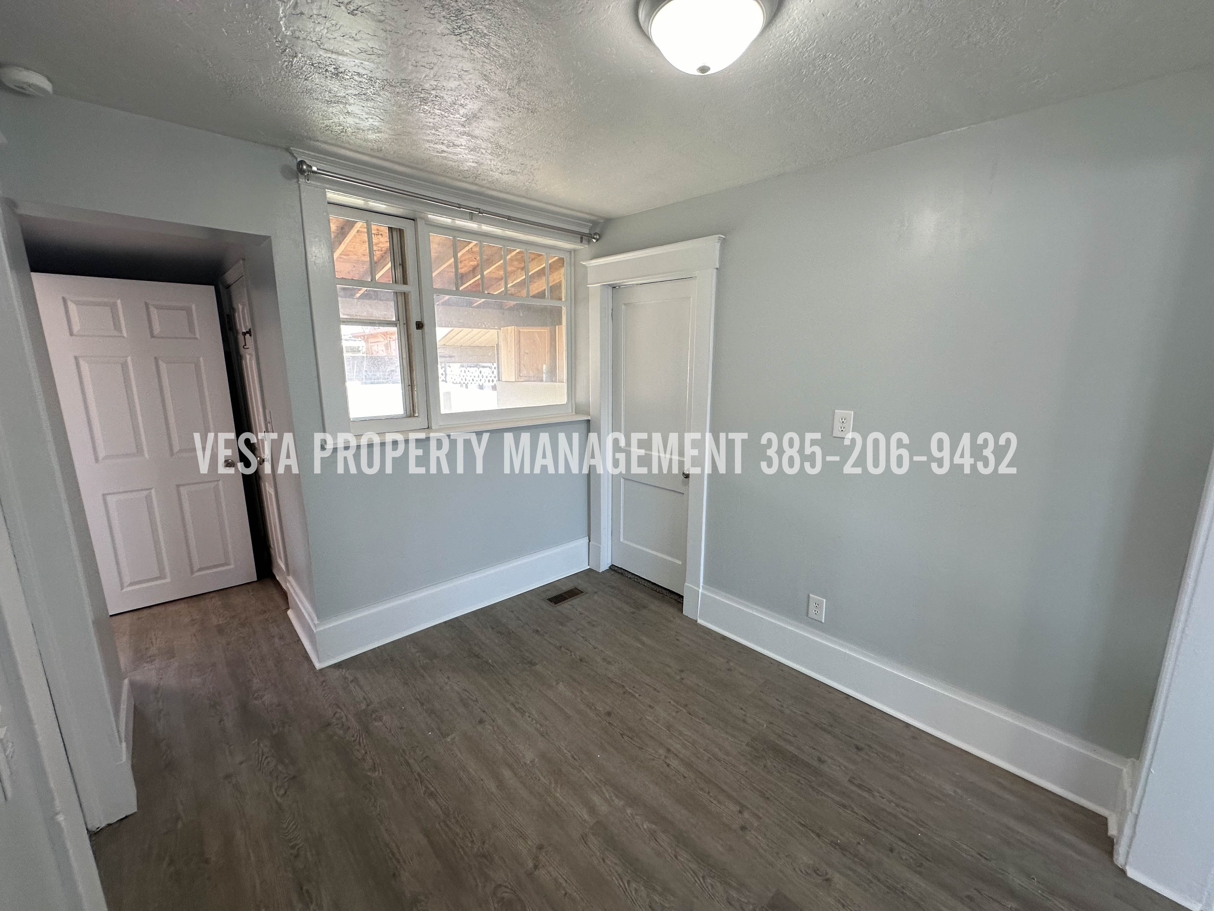 Unfurnished room featuring dark wood-style flooring, a textured ceiling, and a smoke detector