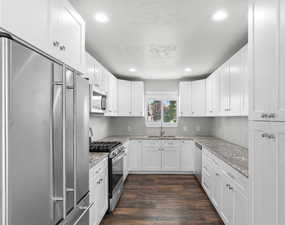 Kitchen featuring stainless steel appliances, white cabinetry, dark wood-style floors, recessed lighting, and light stone countertops