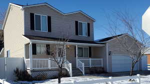 View of front of home with an attached garage, covered porch, and driveway