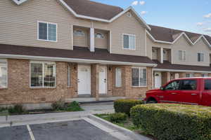 View of front of home featuring uncovered parking, brick siding, and roof with shingles