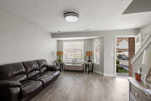 Living area with light wood-type flooring and a textured ceiling