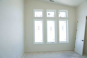 Empty room featuring vaulted ceiling