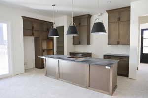 Kitchen with a center island, wood finish cabinetry, decorative light fixtures, and tile patterned floors