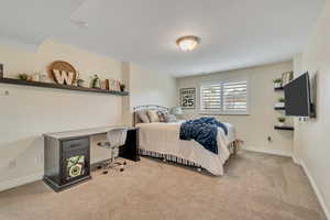 Bedroom featuring light carpet and an office area