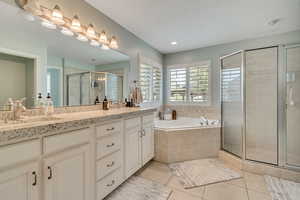 Bathroom with double vanity, light tile patterned floors, a shower stall, and a bath
