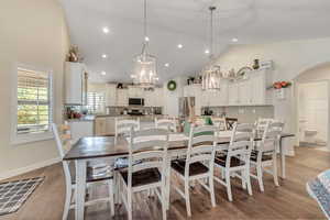 Dining space with lofted ceiling, arched walkways, dark wood-style floors, and hanging lights