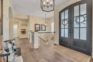 Entryway featuring hanging lights, french doors, light wood-style flooring, and arched walkways