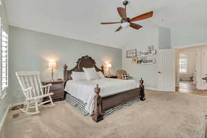 Bedroom featuring light carpet, vaulted ceiling, and ceiling fan