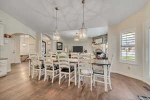Dining room with hardwood / wood-style floors, a chandelier, arched walkways, and lofted ceiling