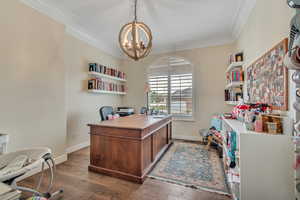 Home office with dark wood-type flooring, hanging lights, and ornamental molding