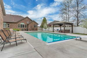 View of swimming pool with a gazebo, patio surround, outdoor furniture, and a fenced backyard
