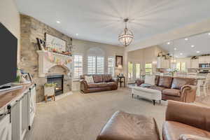 Living area featuring a chandelier, a fireplace, healthy amount of natural light, and light carpet