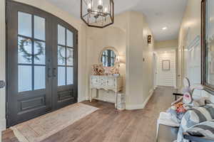 Entryway with hanging lights, wood-type flooring, and french doors