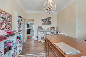 Office space featuring a chandelier, ornamental molding, and dark wood-style flooring