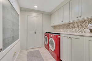 Laundry area with cabinet space, light tile patterned floors, and separate washer and dryer