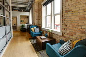 Sitting area with light wood-style flooring and exposed brick wall