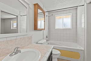 #813 Full bath featuring vanity, Jetted bathtub / shower combination, a textured ceiling, and plenty of natural light