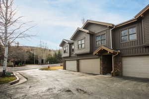 View of home's exterior featuring stone siding, asphalt driveway, board and batten siding, and an attached garage