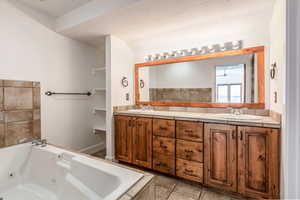 Full bathroom featuring double vanity, a whirlpool tub, and a textured ceiling