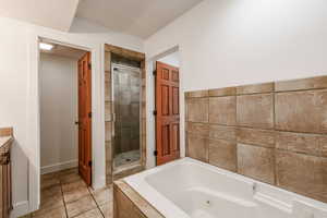 Bathroom featuring a whirlpool tub, vanity, and a stall shower