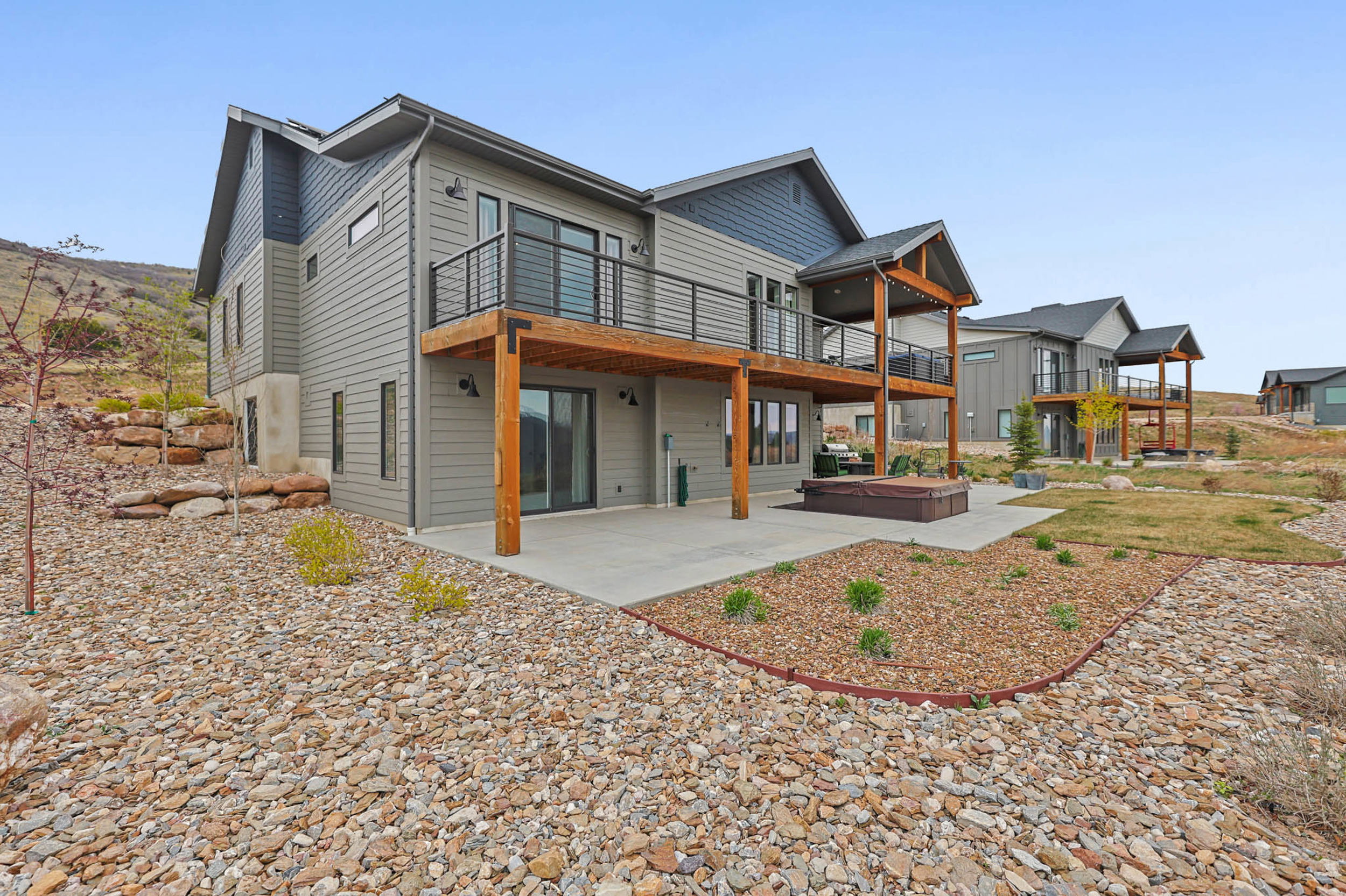 Back of property with a patio area, a deck, and a hot tub