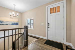 Foyer entrance with dark wood finished floors and a chandelier