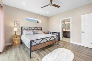 Bedroom with light wood-style flooring, a ceiling fan, recessed lighting, and ensuite bath