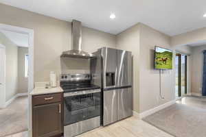 Kitchen with stainless steel appliances, light colored carpet, dark wood finish cabinetry, light stone counters, and recessed lighting