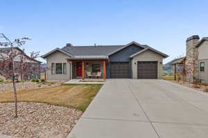 View of front of house with covered porch, roof with shingles, a front yard, concrete driveway, and a garage