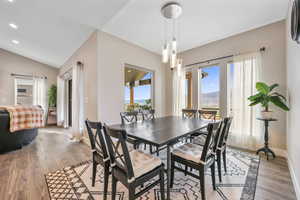 Dining space with wood finished floors, vaulted ceiling, and recessed lighting